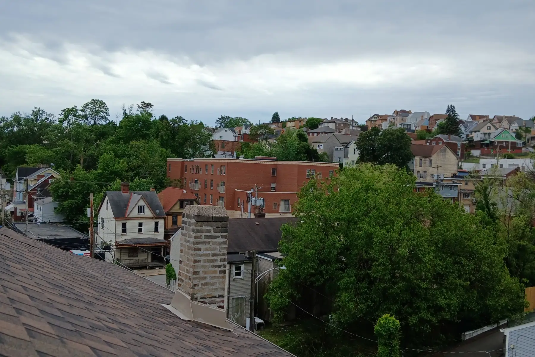 Pittsburgh rooftops and hillside trees seen from the ridge of a finished roof