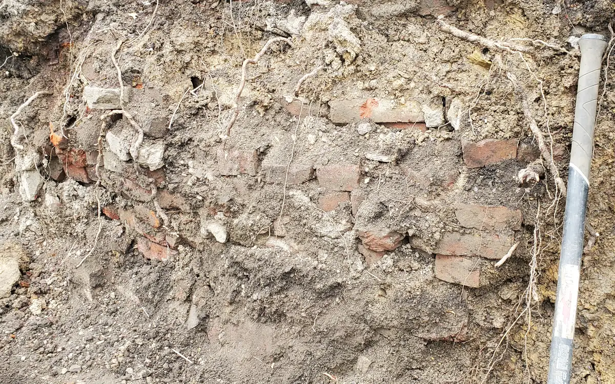 An old brick and stone foundation wall opened up at ground level
