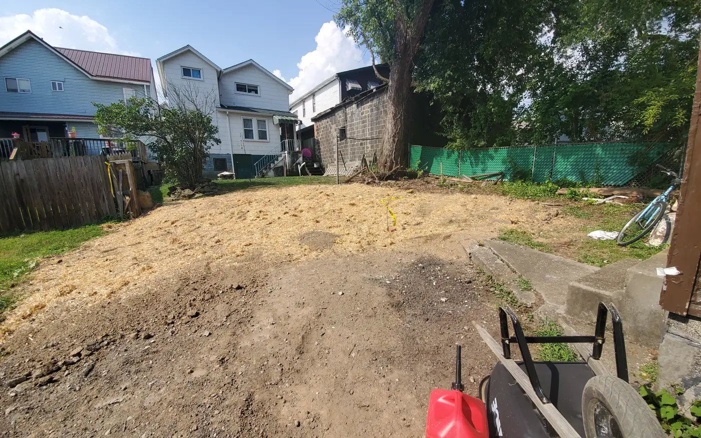 A lot graded flat and cleared down to bare dirt with the house standing behind it
