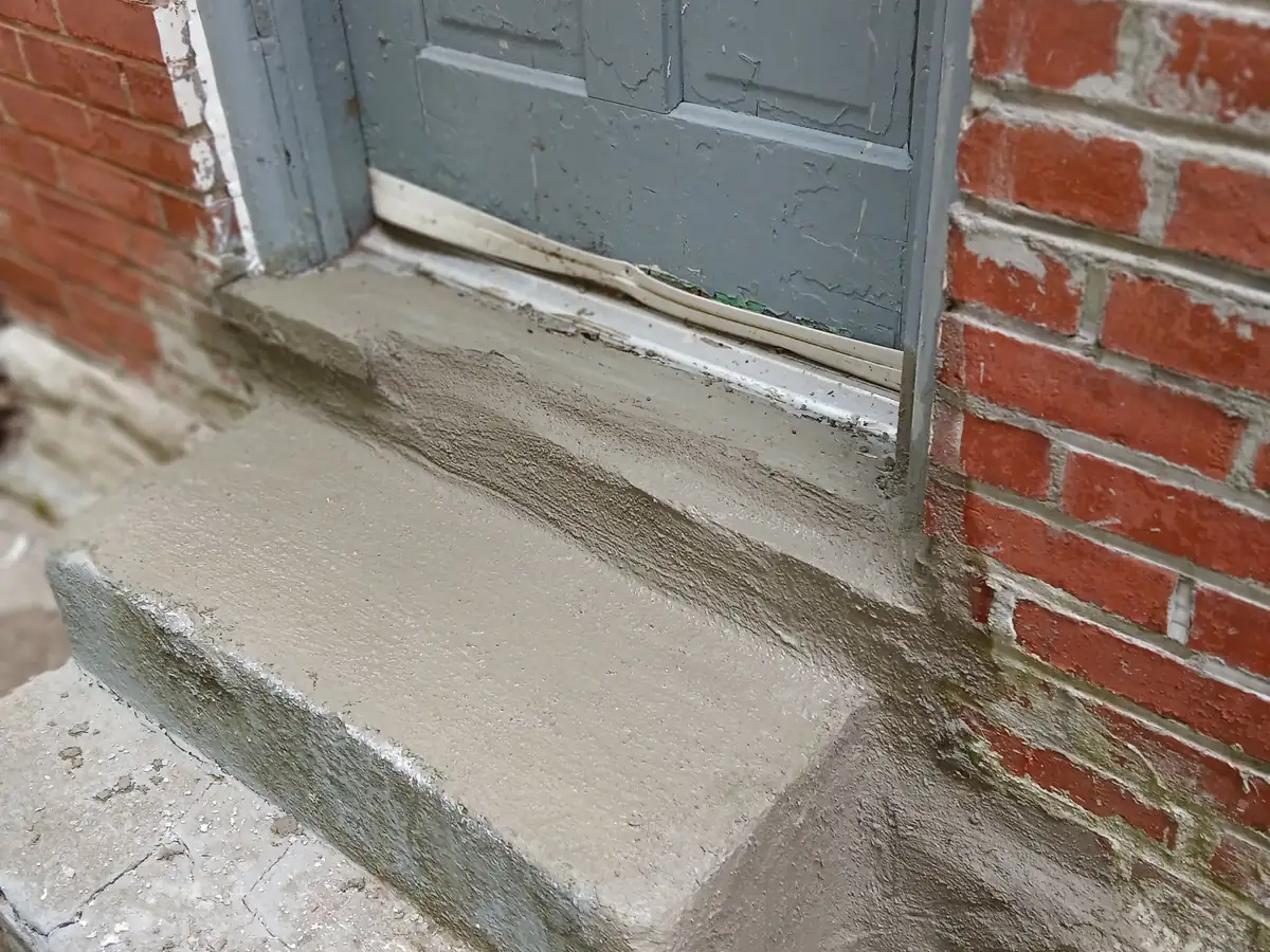 A rebuilt entry step finished flush against the original red brick